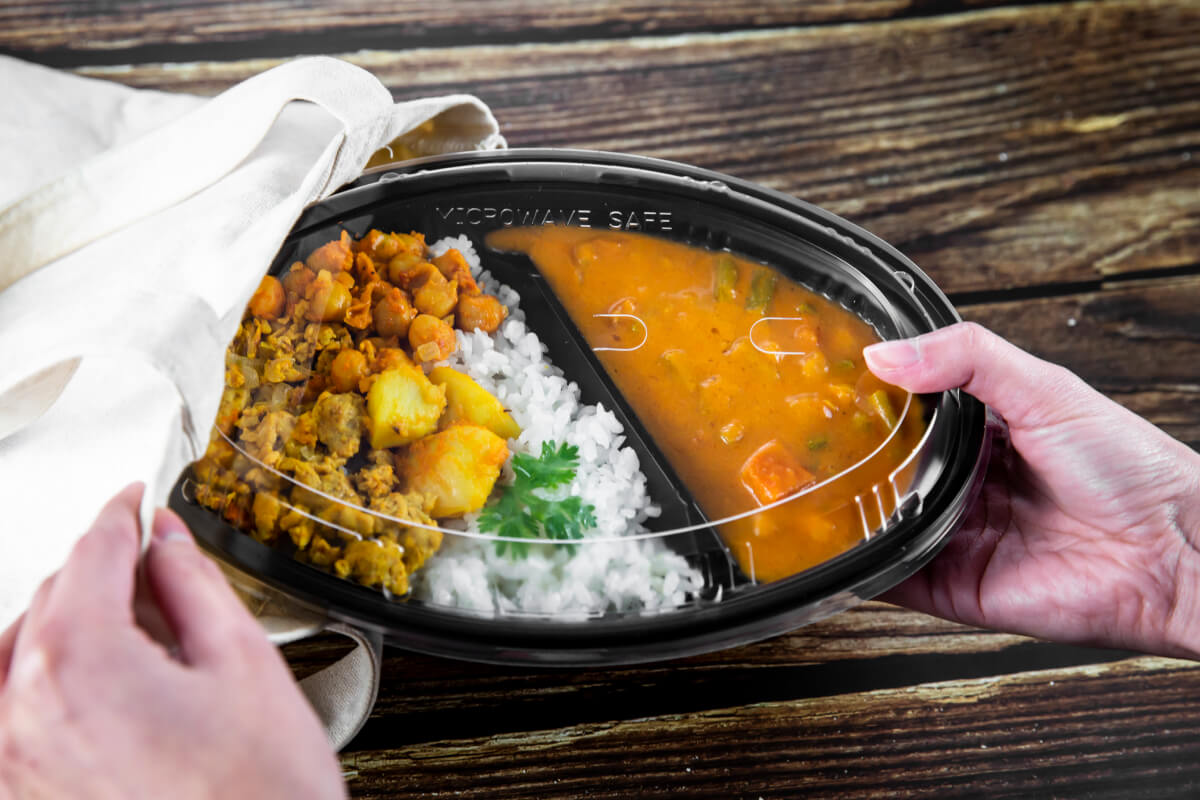 電子レンジ対応の業務用プラスチック容器。様々な惣菜が詰められ、そのまま加熱できる利便性を表している。 