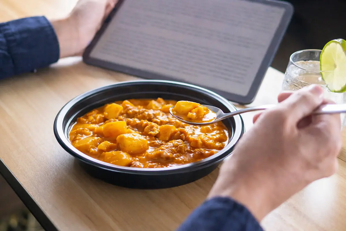 電子レンジ対応や食べやすさなど、選ぶときのチェックポイントを満たしたカレーテイクアウト容器での食事シーン。